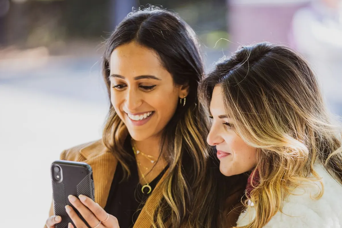 Two friends smiling at a smartphone