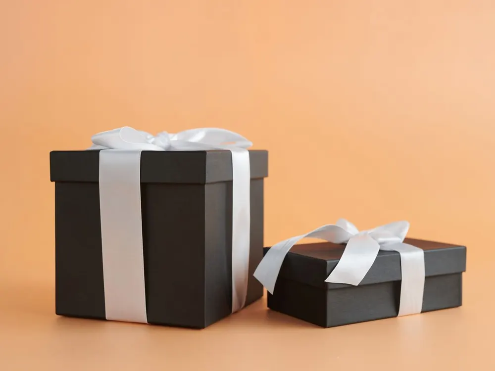 Two black gift boxes tied with white ribbon
